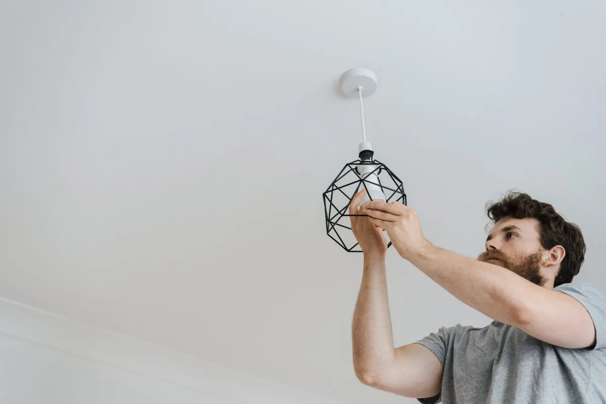 Électricien installant un luminaire au plafond